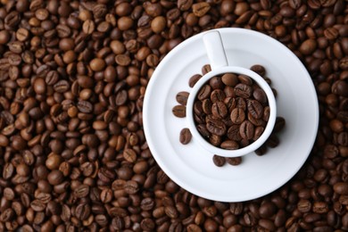 Photo of Cup and saucer on coffee beans, top view. Space for text