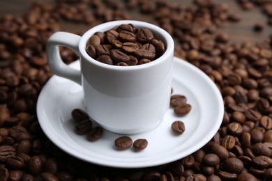 Photo of Aromatic coffee beans, cup and saucer on table, closeup