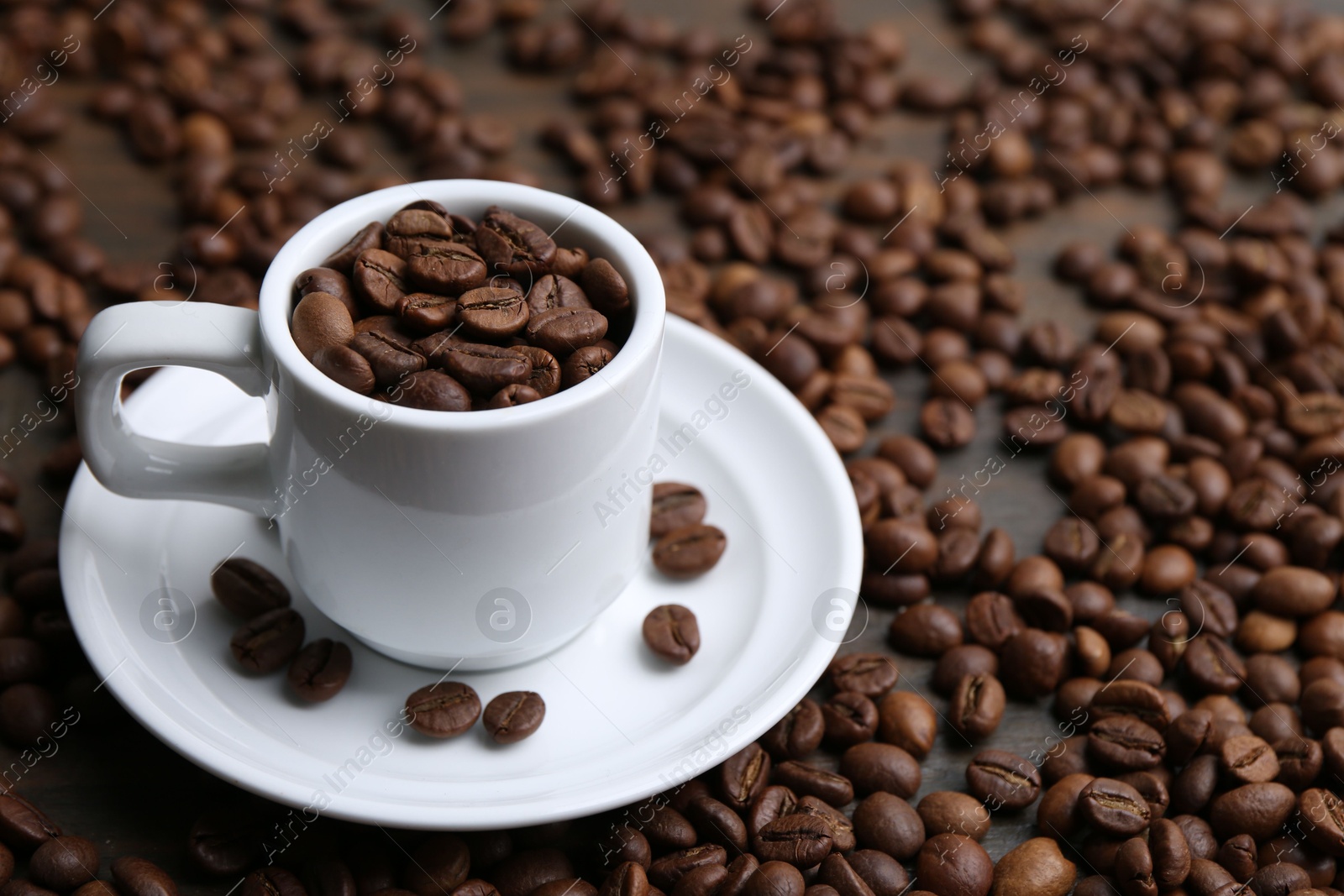 Aromatic coffee beans, cup and saucer on table, closeup. Space for text Photo of Aromatic coffee beans, cup and saucer on table, closeup. Space for text