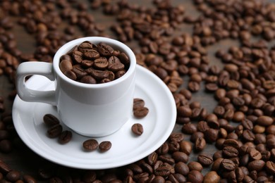 Photo of Aromatic coffee beans, cup and saucer on table, closeup. Space for text