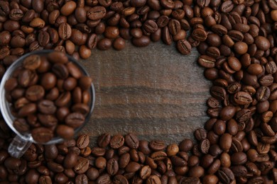 Photo of Aromatic coffee beans and glass cup on wooden table, flat lay. Space for text