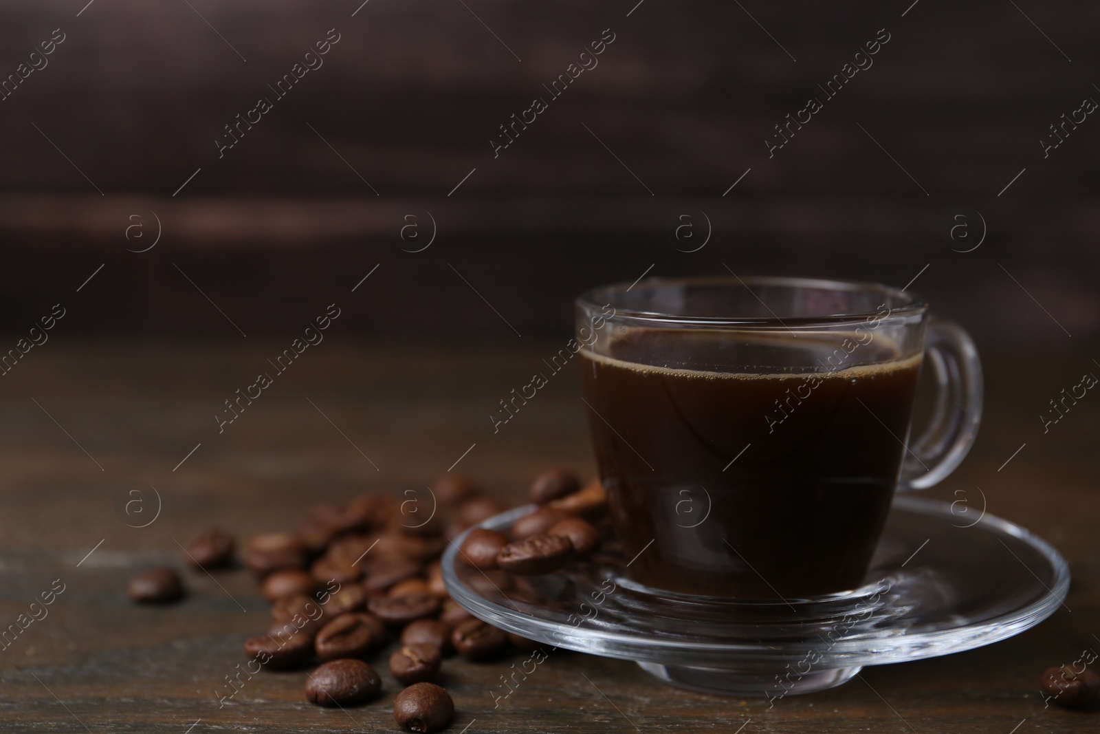Aromatic coffee in glass cup and beans on wooden table, closeup. Space for text Photo of Aromatic coffee in glass cup and beans on wooden table, closeup. Space for text
