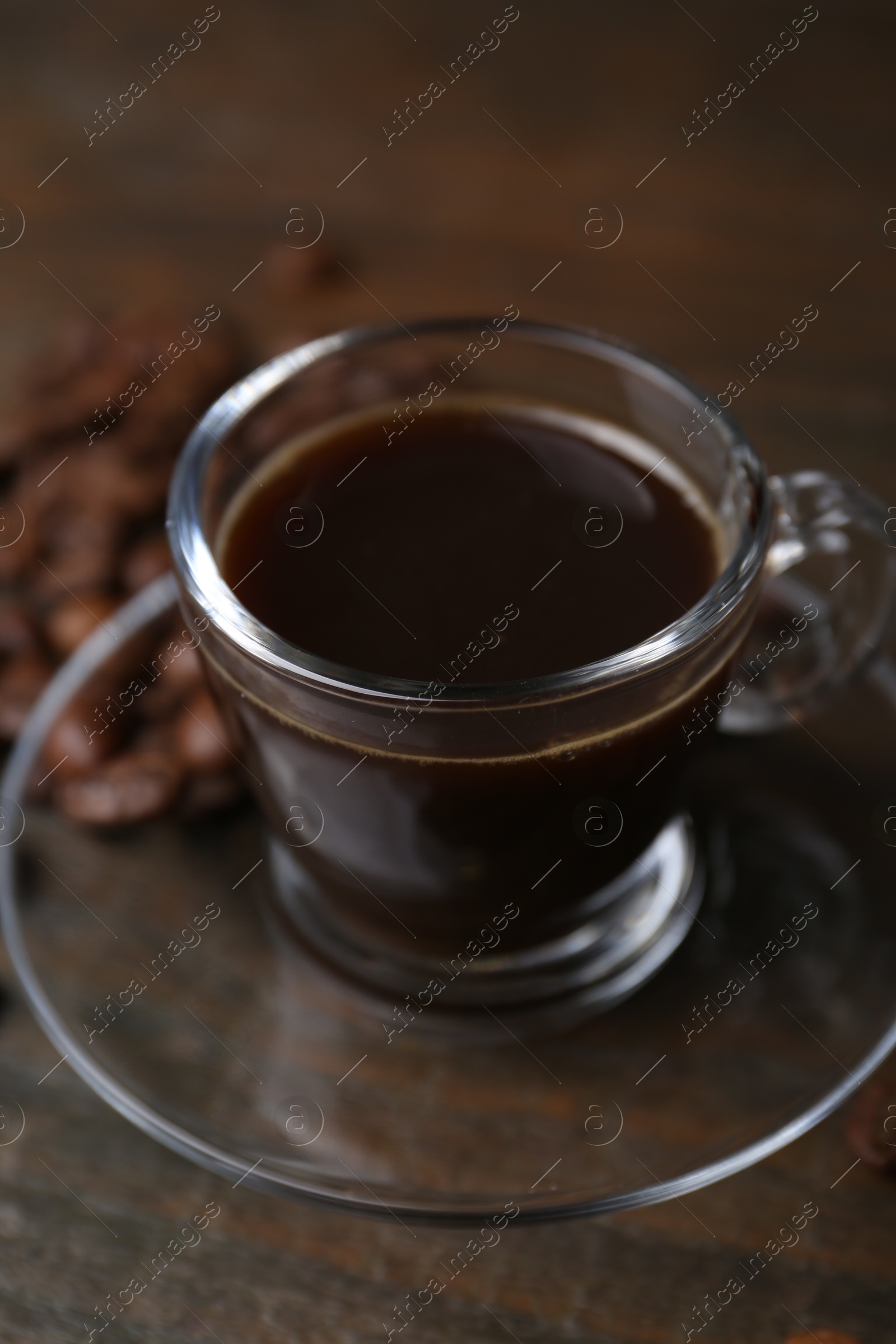 Aromatic coffee in glass cup and beans on wooden table, closeup Photo of Aromatic coffee in glass cup and beans on wooden table, closeup