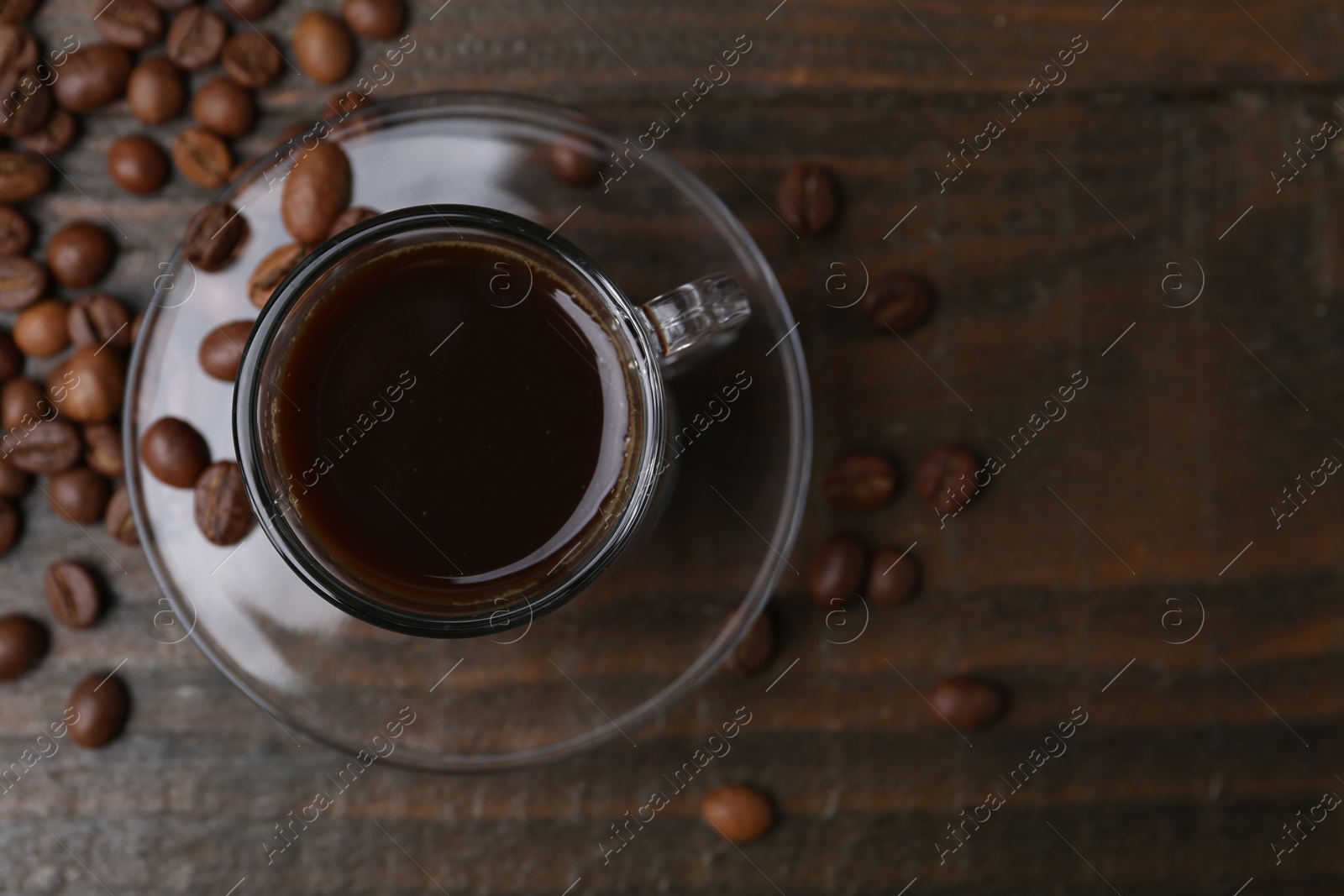 Aromatic coffee in glass cup and beans on wooden table, flat lay. Space for text Photo of Aromatic coffee in glass cup and beans on wooden table, flat lay. Space for text
