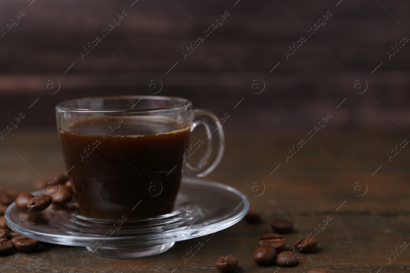 Aromatic coffee in glass cup and beans on wooden table, closeup. Space for text Photo of Aromatic coffee in glass cup and beans on wooden table, closeup. Space for text