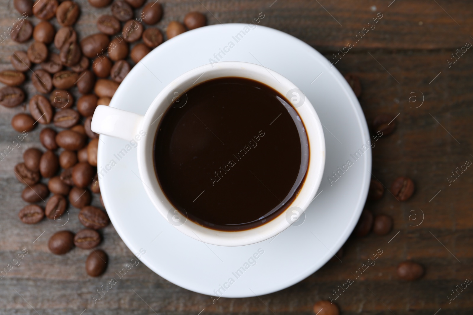 Aromatic coffee in cup and beans on wooden table, flat lay Photo of Aromatic coffee in cup and beans on wooden table, flat lay