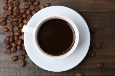 Photo of Aromatic coffee in cup and beans on wooden table, flat lay