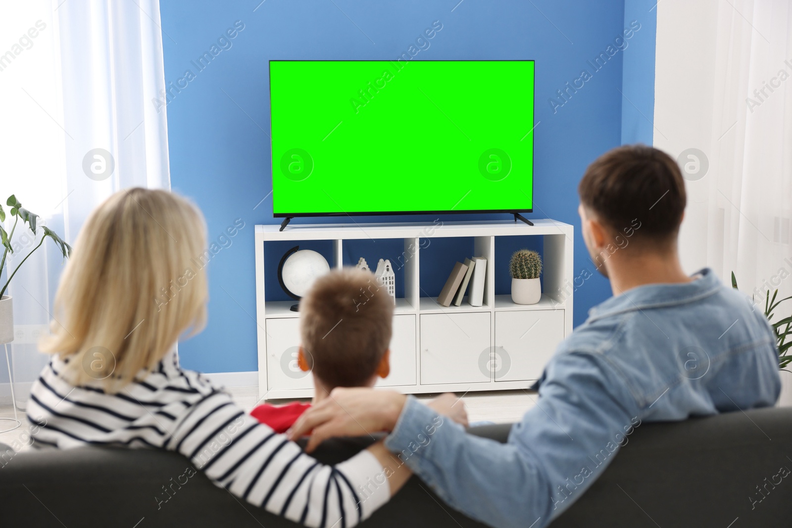 Image of Family watching modern TV set with green screen at home. Chroma key compositing