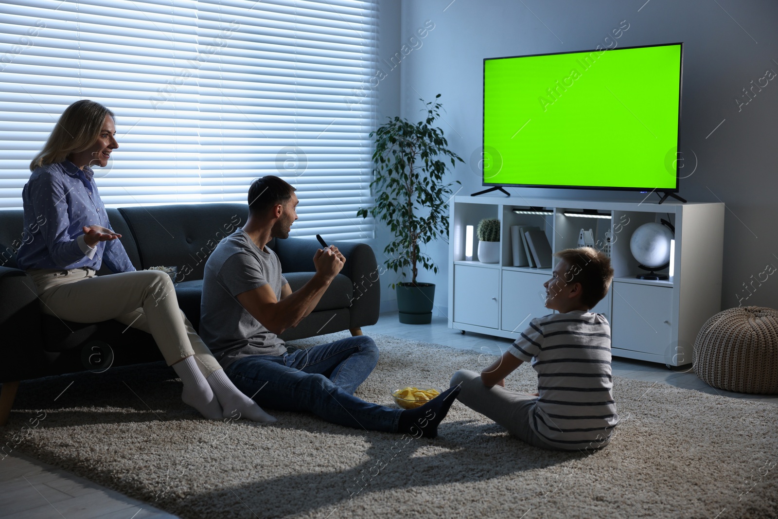 Family watching modern TV set with green screen at home in evening. Chroma key compositing Image of Family watching modern TV set with green screen at home in evening. Chroma key compositing