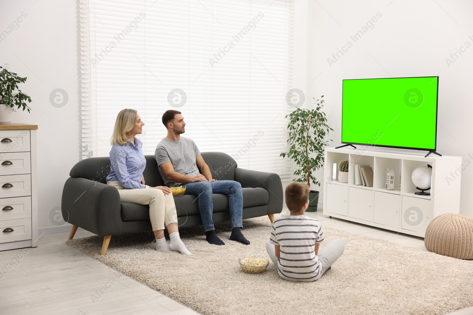 Image of Family watching modern TV set with green screen at home. Chroma key compositing
