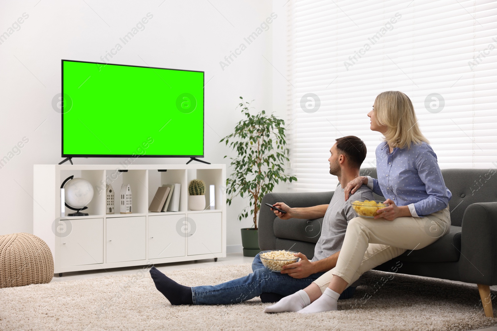 Couple watching TV set with green screen in living room. Chroma key compositing Image of Couple watching TV set with green screen in living room. Chroma key compositing
