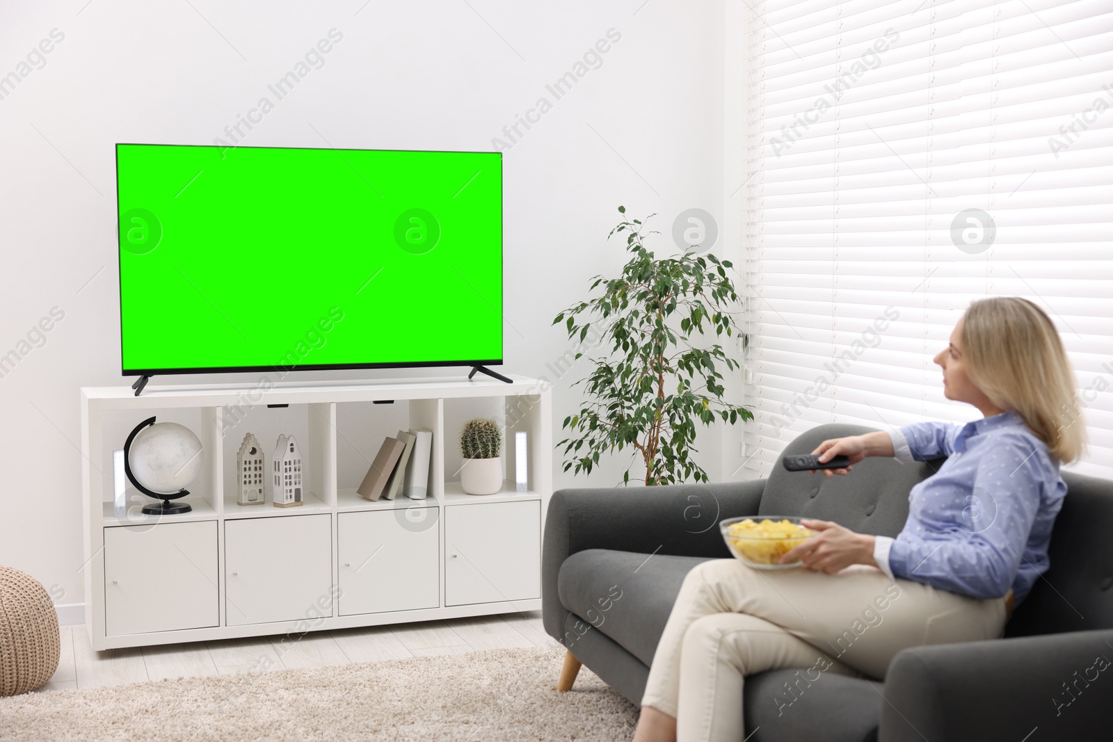 Woman watching TV set with green screen in room. Chroma key compositing Image of Woman watching TV set with green screen in room. Chroma key compositing