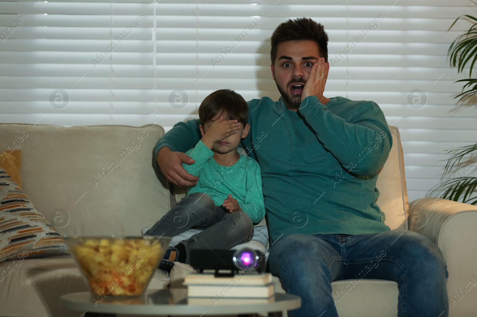 Emotional young man and his son watching movie using video projector at home Photo of Emotional young man and his son watching movie using video projector at home