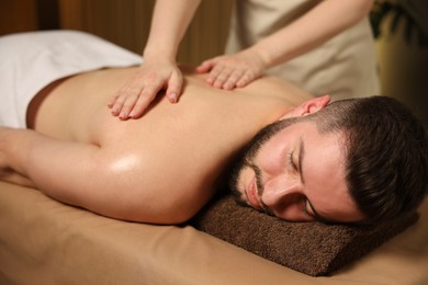 Photo of Man receiving relaxing massage in spa salon