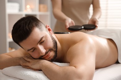 Photo of Man receiving relaxing massage with stones in spa salon