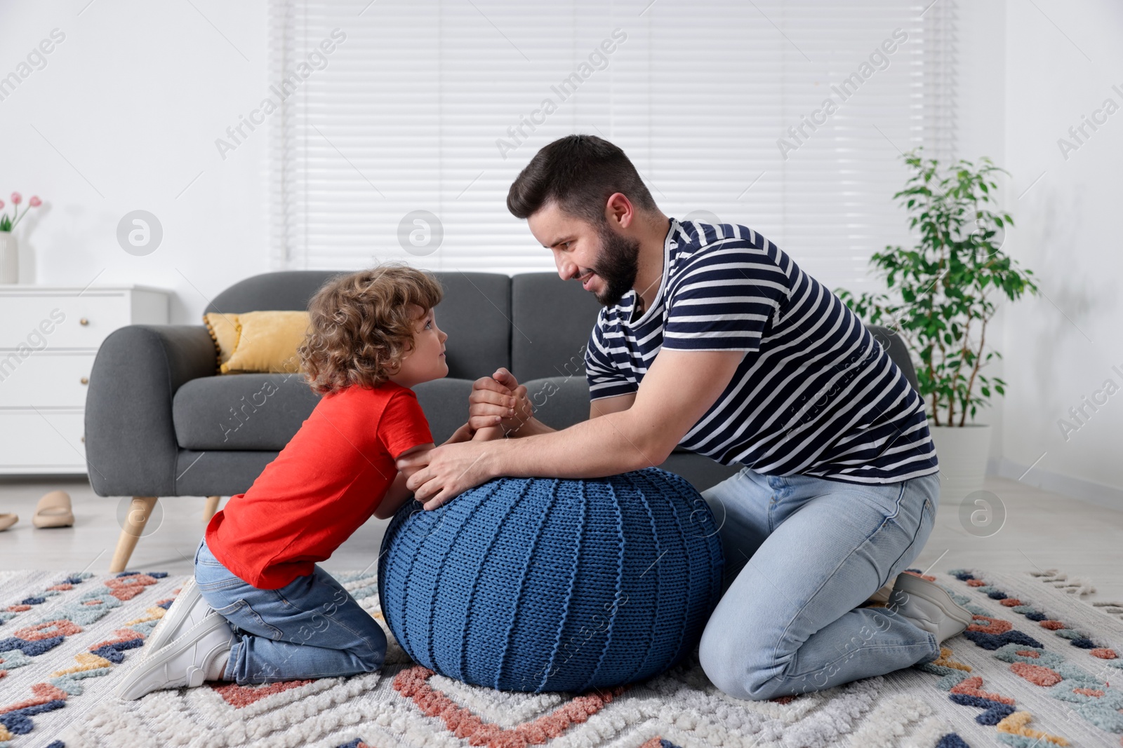 Happy father with his son arm wrestling and spending time together at home Photo of Happy father with his son arm wrestling and spending time together at home