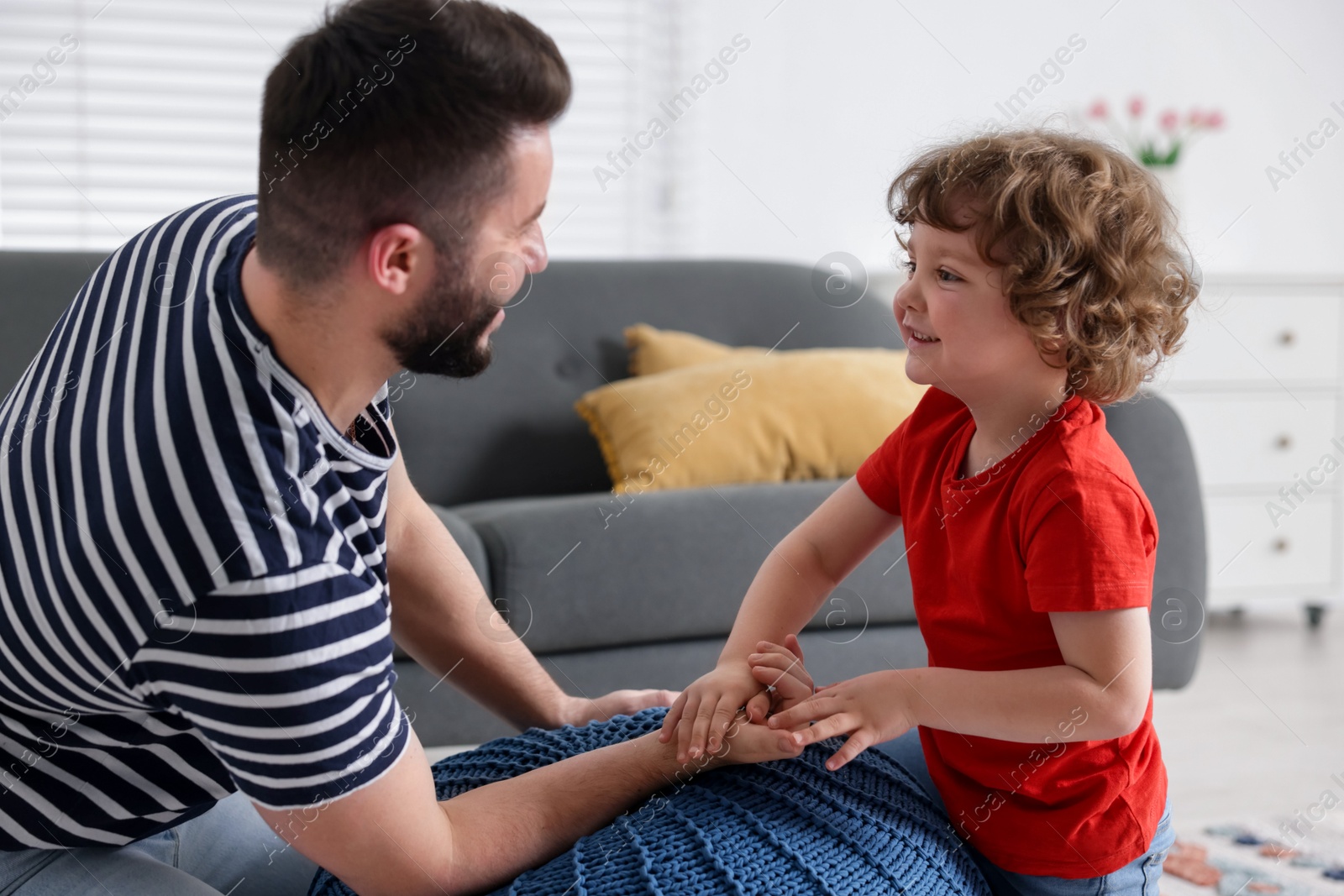 Happy father with his son arm wrestling and spending time together at home Photo of Happy father with his son arm wrestling and spending time together at home