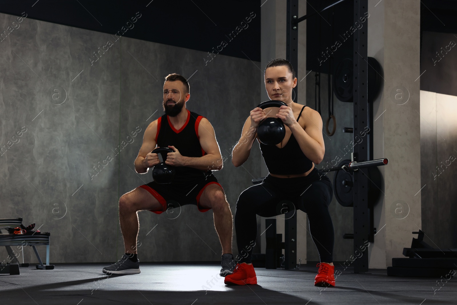 Photo of Athletic couple training with kettlebells in gym