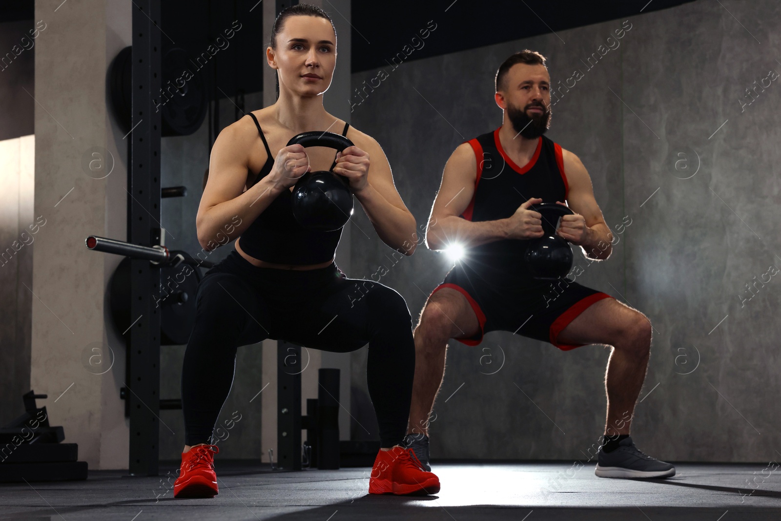 Photo of Athletic couple training with kettlebells in gym