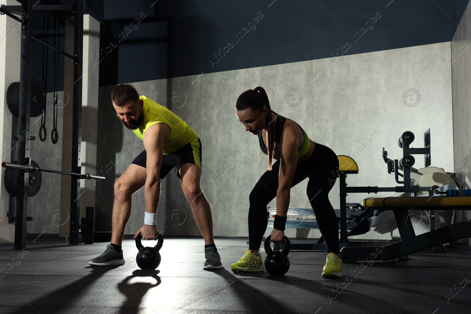 Photo of Athletic couple training with kettlebells in gym