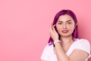 Photo of Beautiful woman with bright purple hair and tattoo in Latin on pink background. Space for text