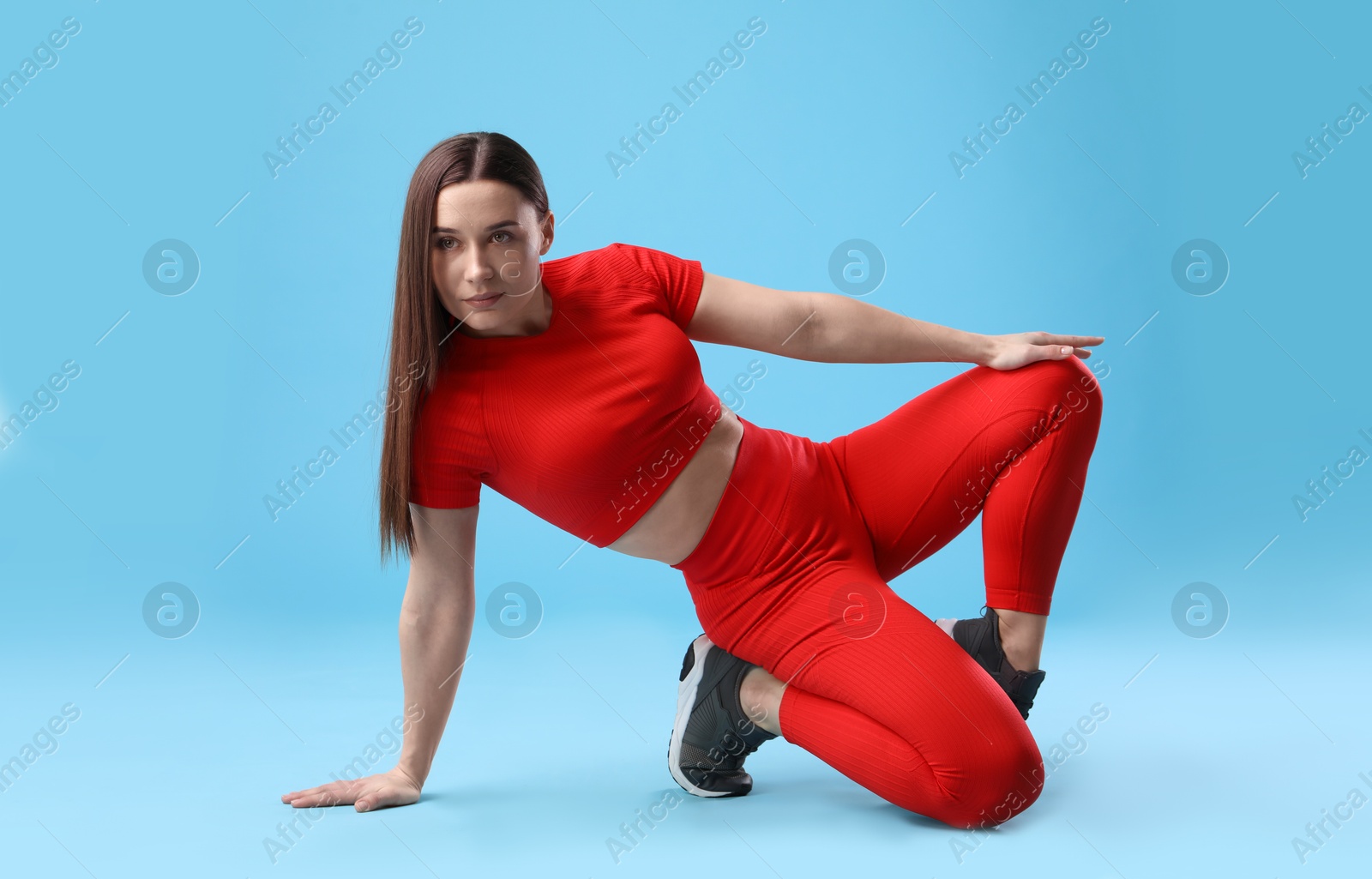 Woman in sportswear posing on light blue background Photo of Woman in sportswear posing on light blue background