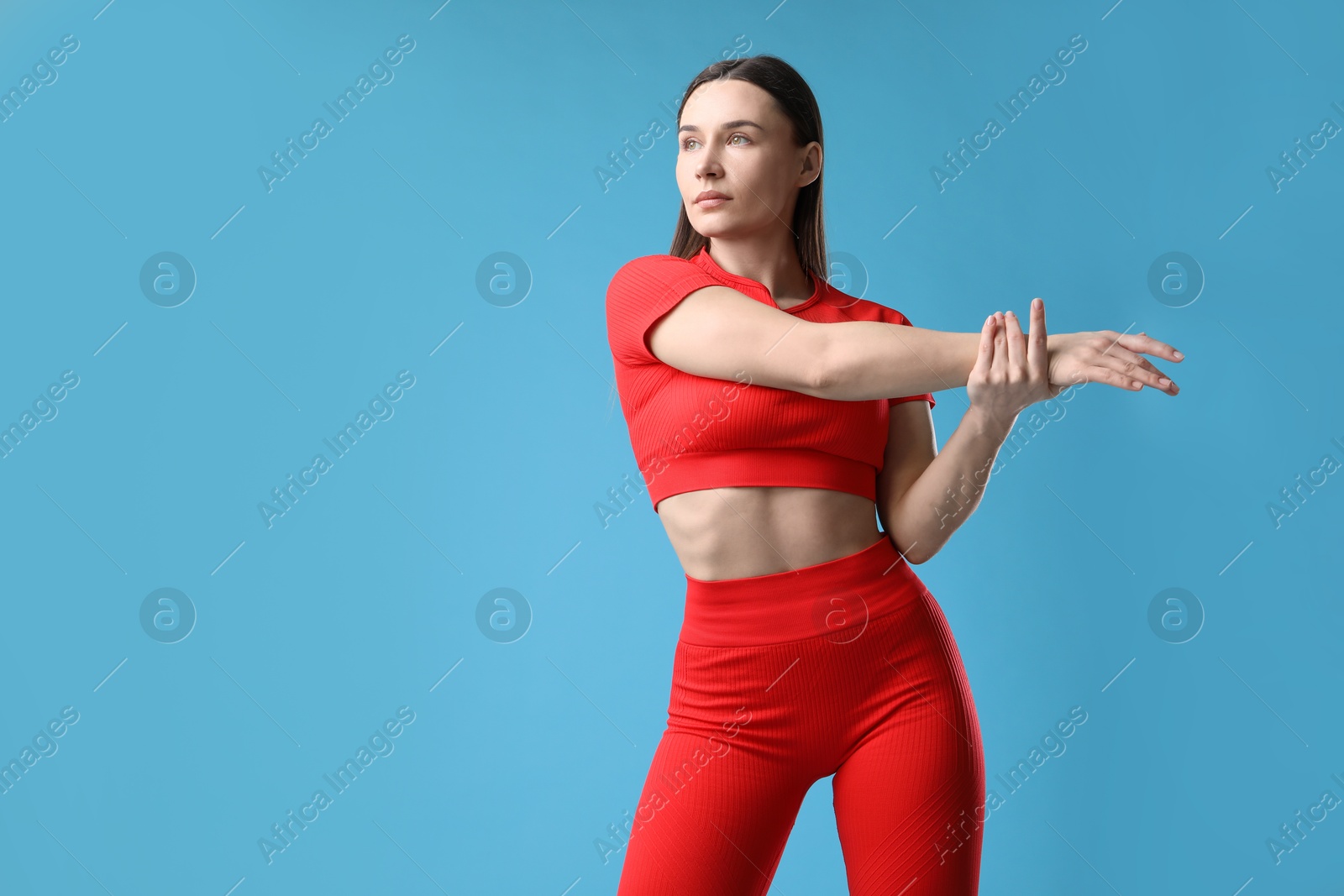 Woman in sportswear exercising on light blue background, space for text Photo of Woman in sportswear exercising on light blue background, space for text