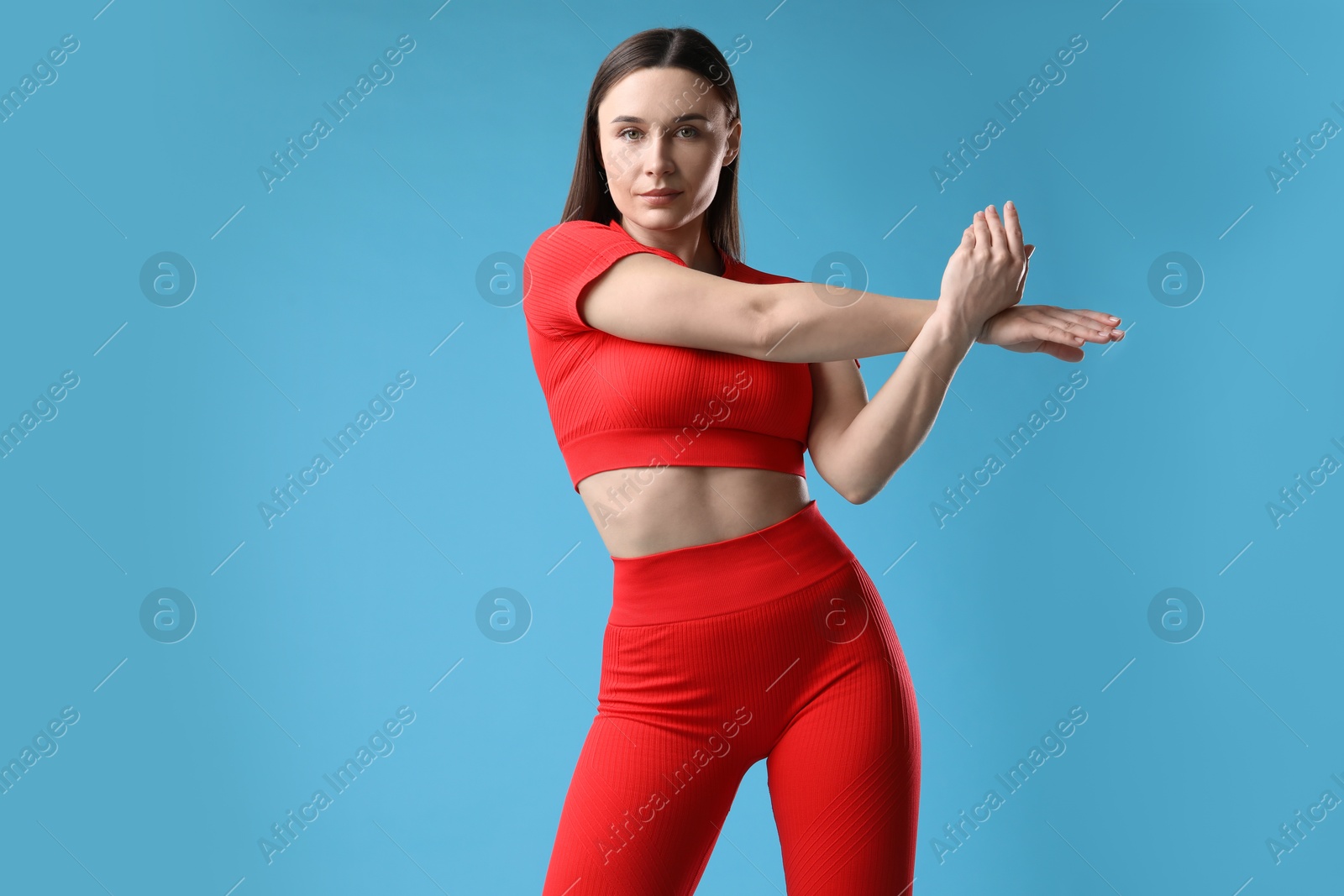 Woman in sportswear exercising on light blue background, space for text Photo of Woman in sportswear exercising on light blue background, space for text