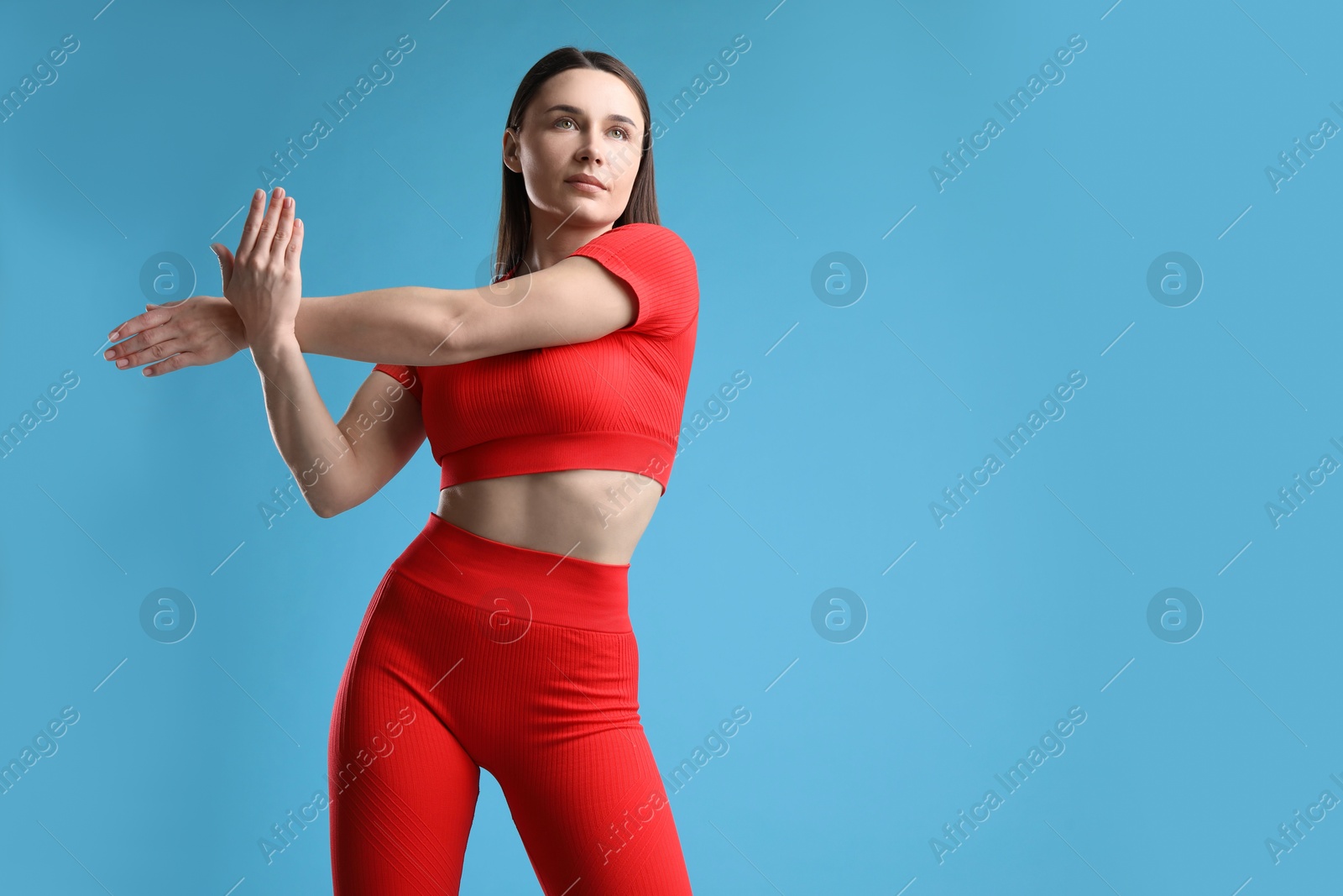 Woman in sportswear exercising on light blue background, space for text Photo of Woman in sportswear exercising on light blue background, space for text