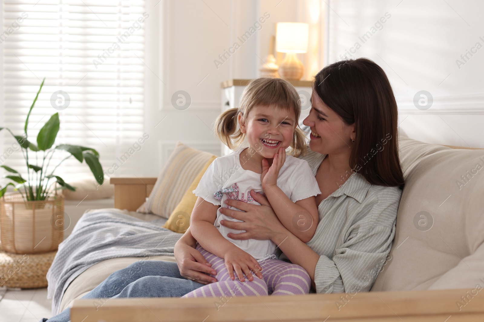 Happy mother and her cute daughter on sofa at home Photo of Happy mother and her cute daughter on sofa at home