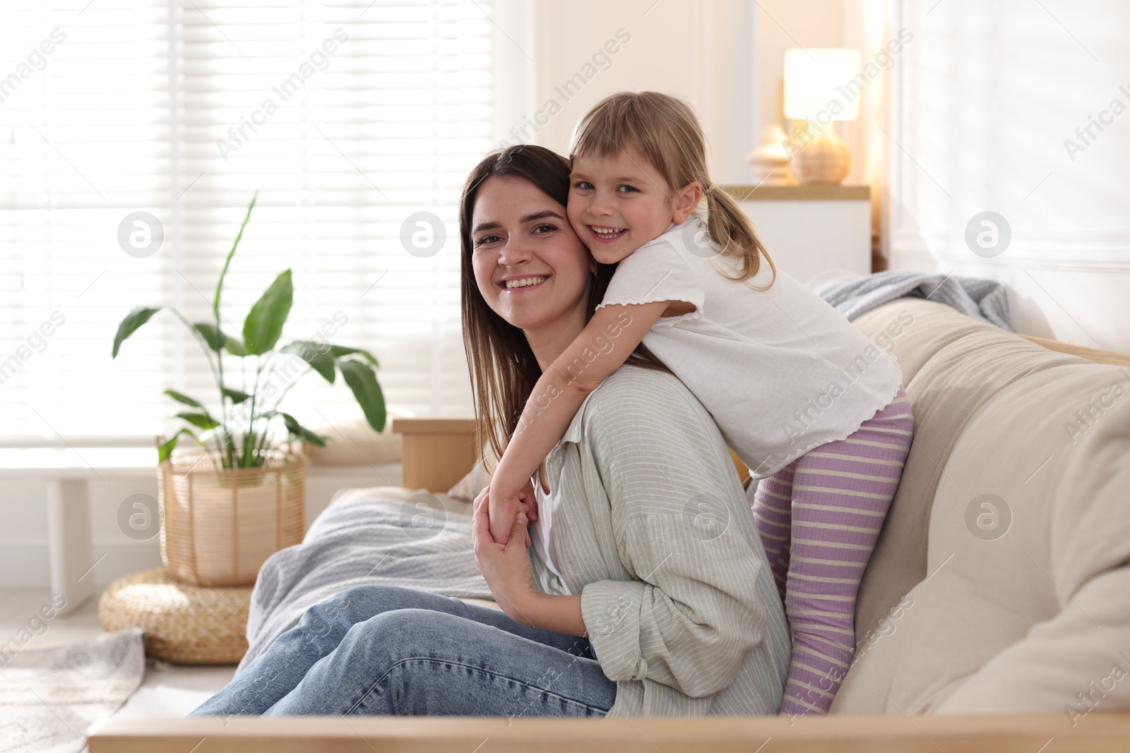Happy mother and her cute daughter on sofa at home Photo of Happy mother and her cute daughter on sofa at home