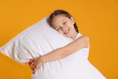 Photo of Cute girl with pillow on orange background