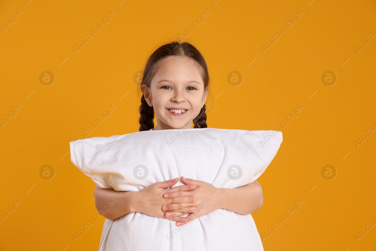 Photo of Cute girl with pillow on orange background