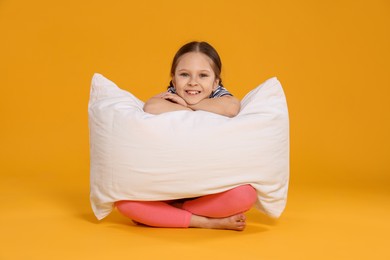Photo of Cute girl with pillow on orange background