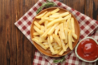 Photo of Tasty french fries served with ketchup and rosemary on wooden table, top view