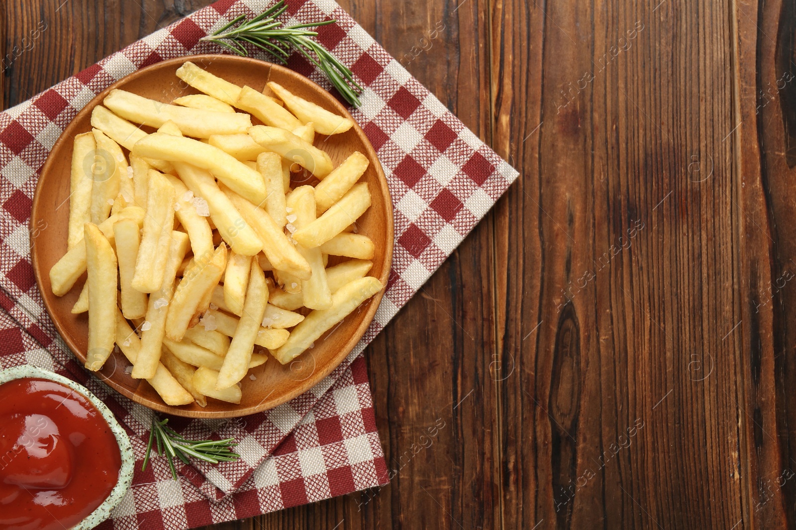 Tasty french fries served with ketchup and rosemary on wooden table, top view. Space for text Photo of Tasty french fries served with ketchup and rosemary on wooden table, top view. Space for text
