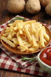 Photo of Tasty french fries served with ketchup and rosemary on wooden table, closeup