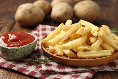 Photo of Tasty french fries served with ketchup and rosemary on wooden table, closeup