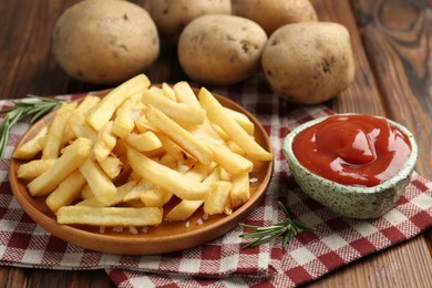 Photo of Tasty french fries served with ketchup and rosemary on wooden table, closeup