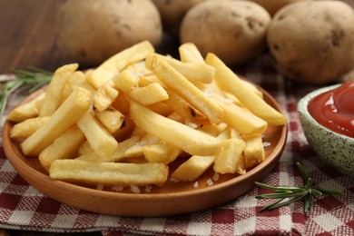 Photo of Tasty french fries served with ketchup and rosemary on table, closeup