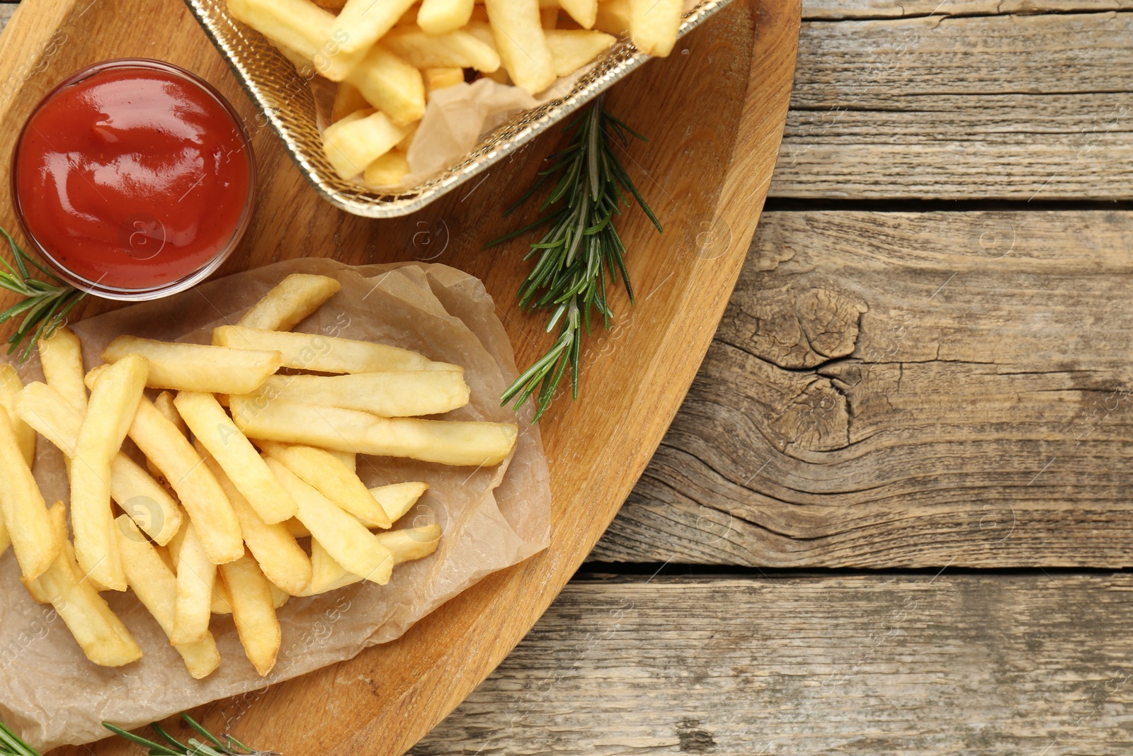 Tasty french fries served with ketchup and rosemary on wooden table, top view. Space for text Photo of Tasty french fries served with ketchup and rosemary on wooden table, top view. Space for text
