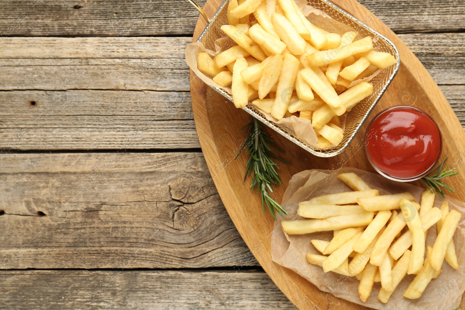 Tasty french fries served with ketchup and rosemary on wooden table, top view. Space for text Photo of Tasty french fries served with ketchup and rosemary on wooden table, top view. Space for text
