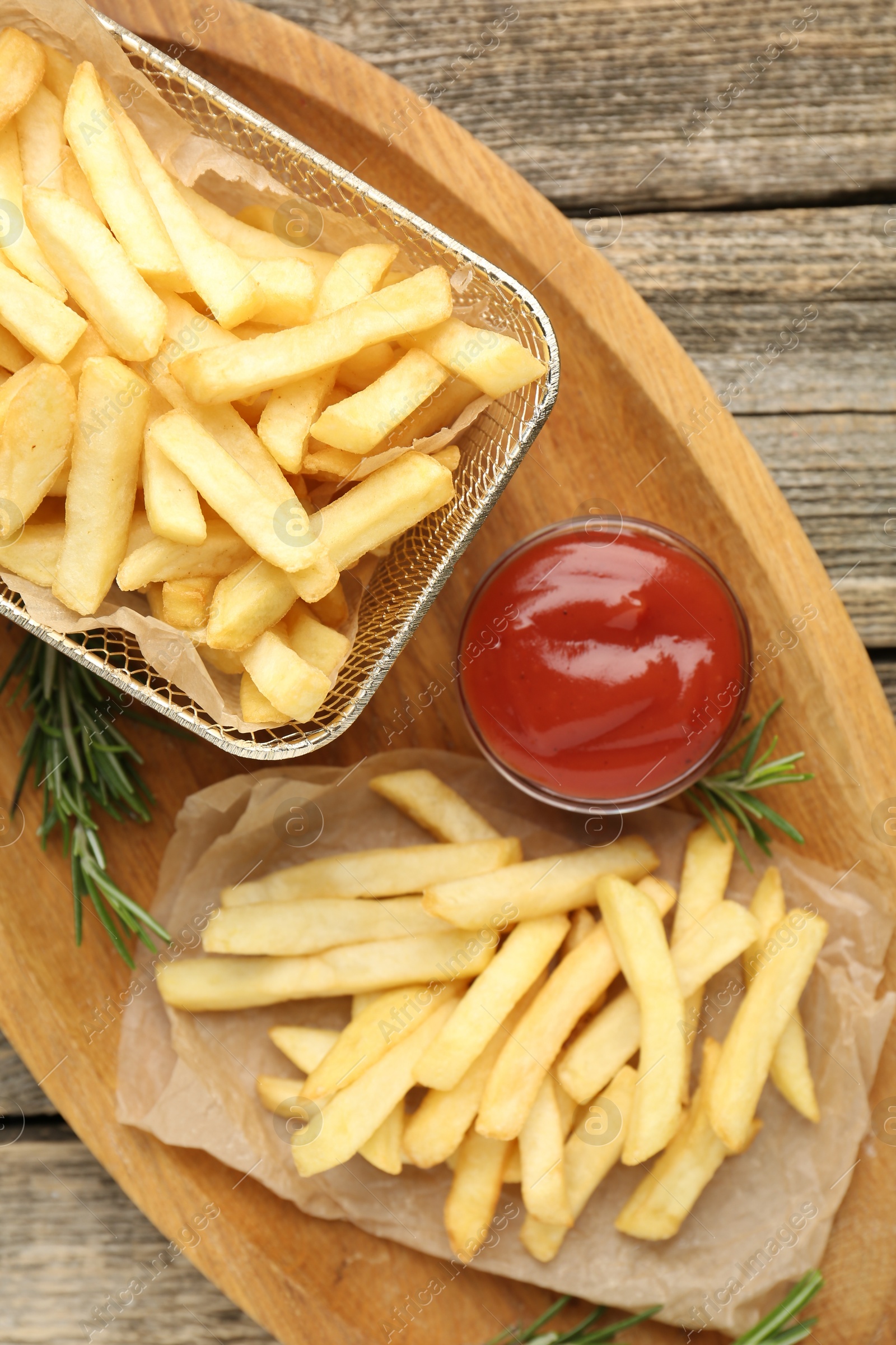 Tasty french fries served with ketchup and rosemary on wooden table, top view Photo of Tasty french fries served with ketchup and rosemary on wooden table, top view