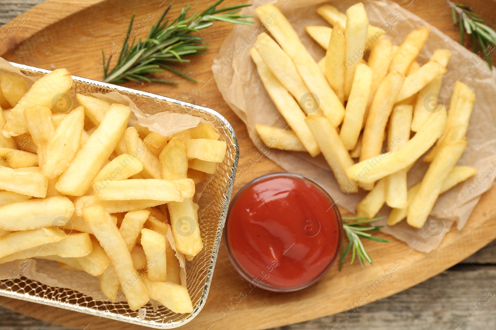 Tasty french fries served with ketchup and rosemary on wooden table, top view Photo of Tasty french fries served with ketchup and rosemary on wooden table, top view