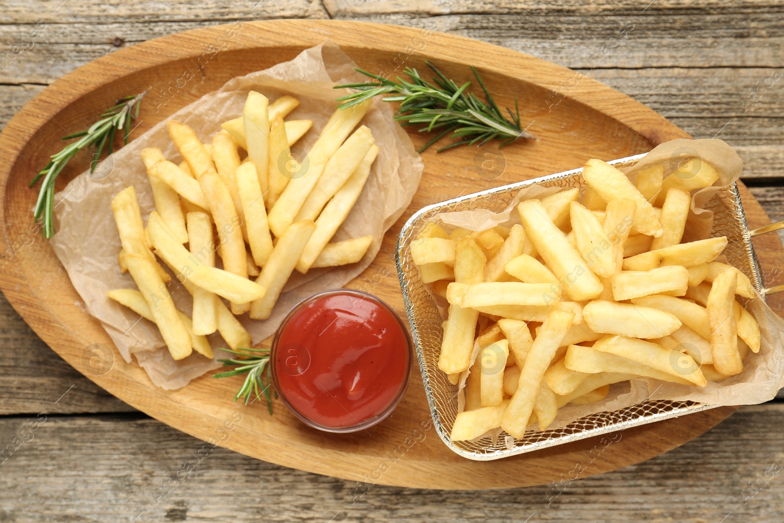 Tasty french fries served with ketchup and rosemary on wooden table, top view Photo of Tasty french fries served with ketchup and rosemary on wooden table, top view
