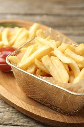 Photo of Tasty french fries served with ketchup on wooden table, closeup