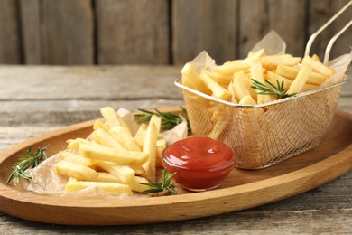 Photo of Tasty french fries served with ketchup and rosemary on wooden table, closeup