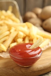Photo of Tasty french fries served with ketchup on wooden table, closeup