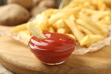 Photo of Tasty french fries served with ketchup on wooden table, closeup