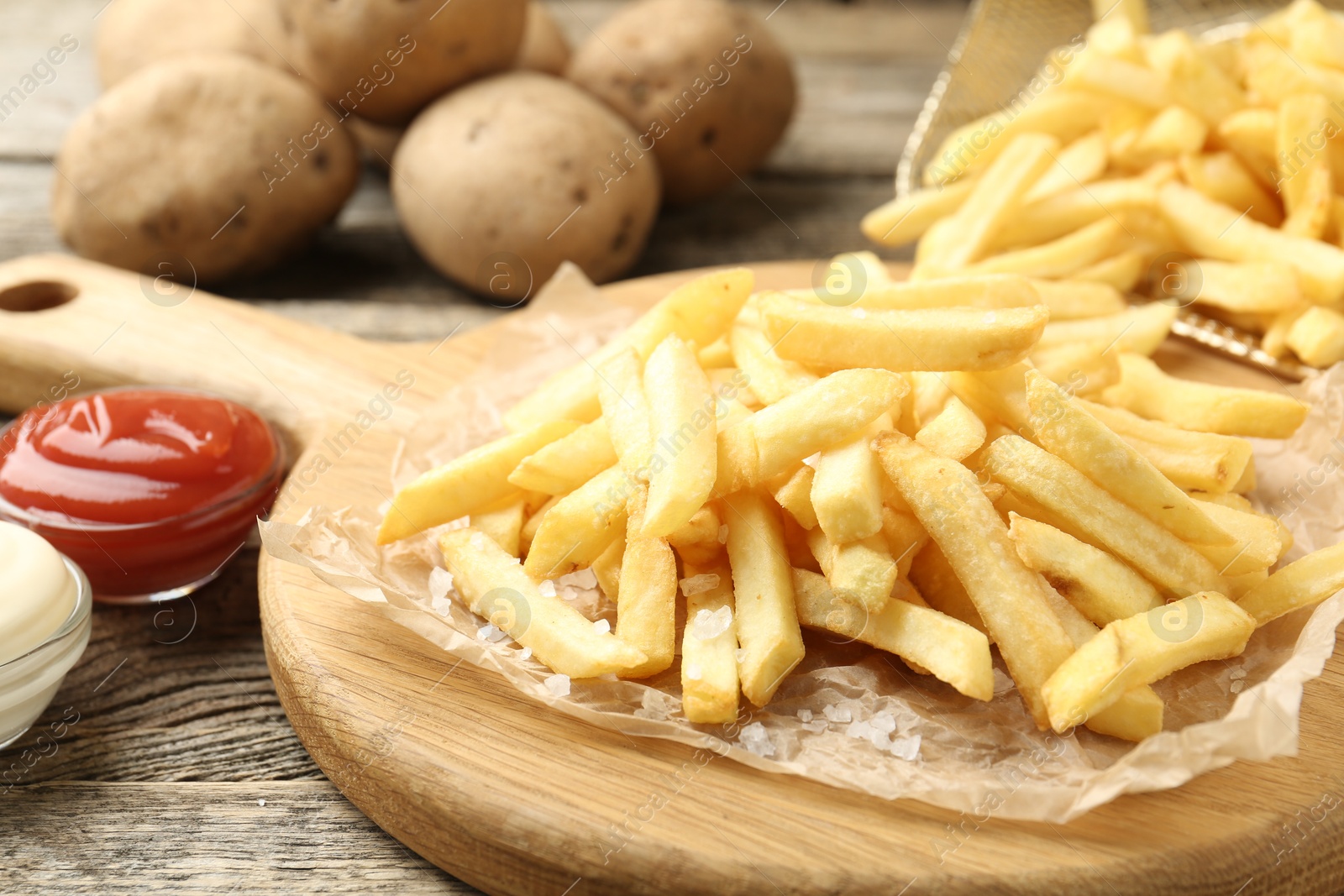 Photo of Tasty french fries served with sauces on wooden table, closeup